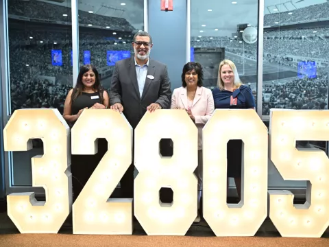Representatives from United Against Poverty, Lift Orlando, AdventHealth for Children and KPMG stand behind a lighted 32805 sign.