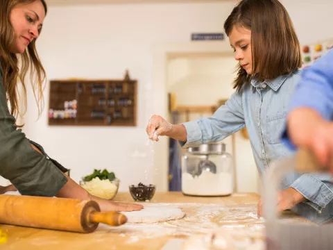 A mother cooking with her kids in the kitchen.