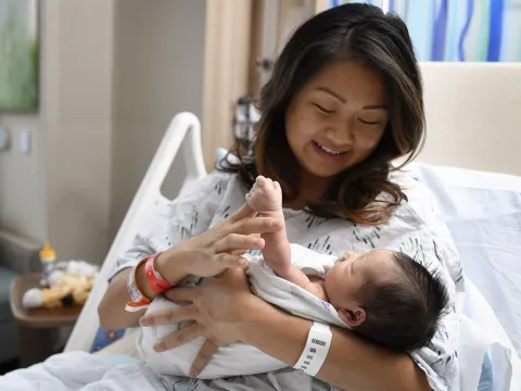 Mother holding her newborn baby in a hospital bed