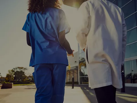 Two physicians at Florida Hospital Cancer Institute walk towards the hospital's front doors