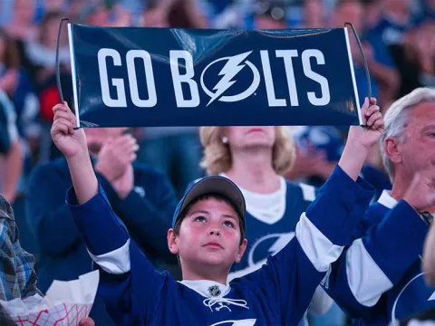 Young Tampa Bay Lightning fan holding a "Go Bolts" sign.
