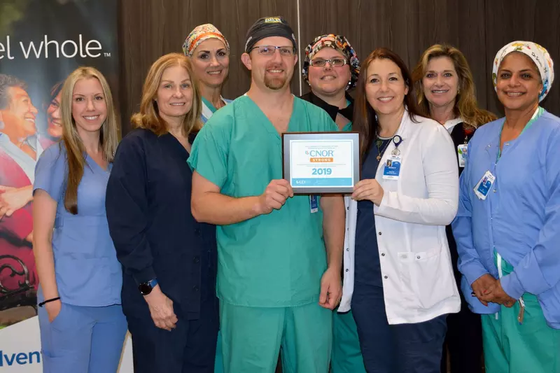 A mixed group of eight doctors and nurses in their scrubs holding an award.