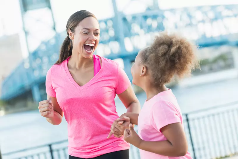 Mother and Daughter Laughing as They Jog Together Along The Water Front.