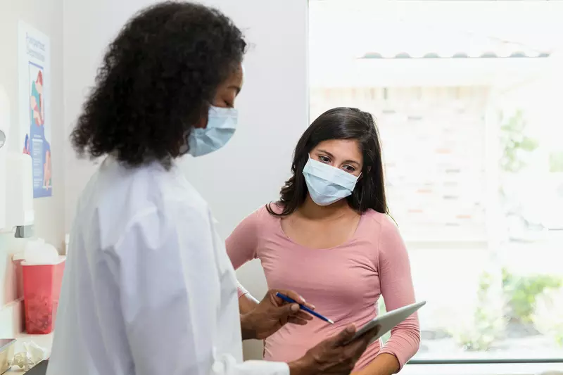 Female doctor goes over a medical chart with a female patient.