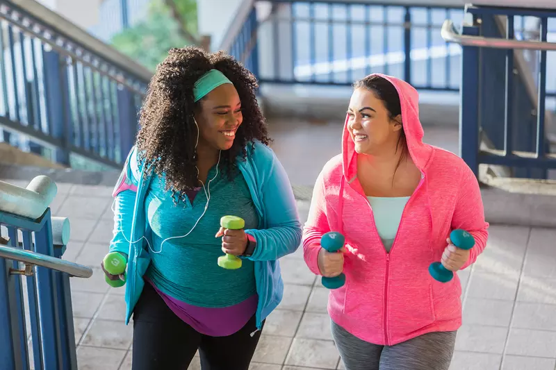 A Pair of Ladies, in Brightly Colored Clothing, Go Jogging in the City with Hand Weights.