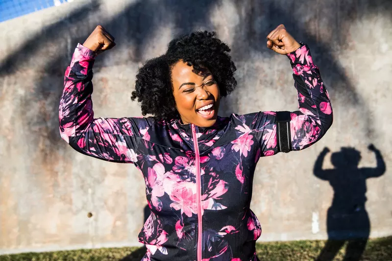 A Woman Triumphantly Flexes Her Arms After a Run in the Park 