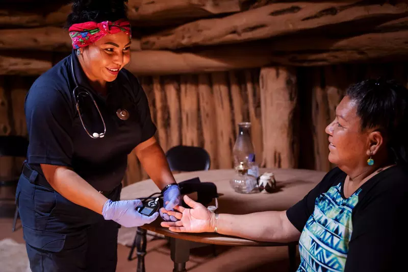 A Native American woman nurse that is about to do a test on a Native American patient.