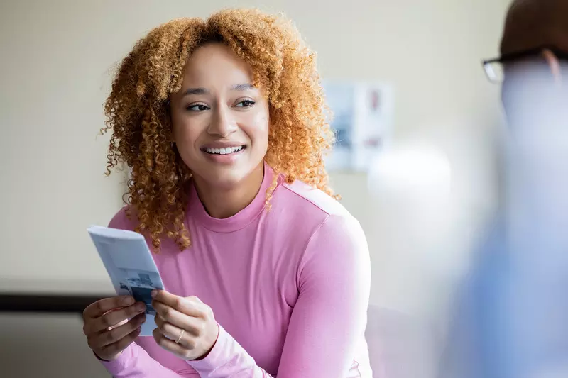 A Woman Smiles as She Listens to a Physician While Holding a Pamphlet. 