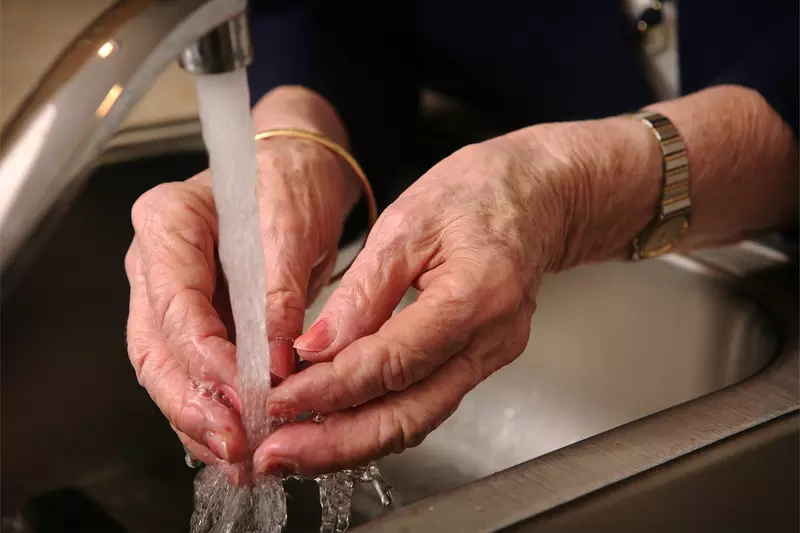 A Close Up of a Senior Woman Washing Her Hands in the Kitchen Sink