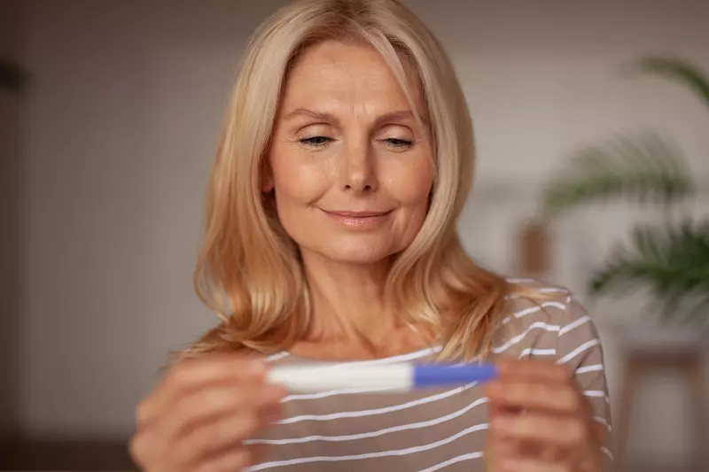 A Woman Smiles as She Looks at a Pregnancy Test