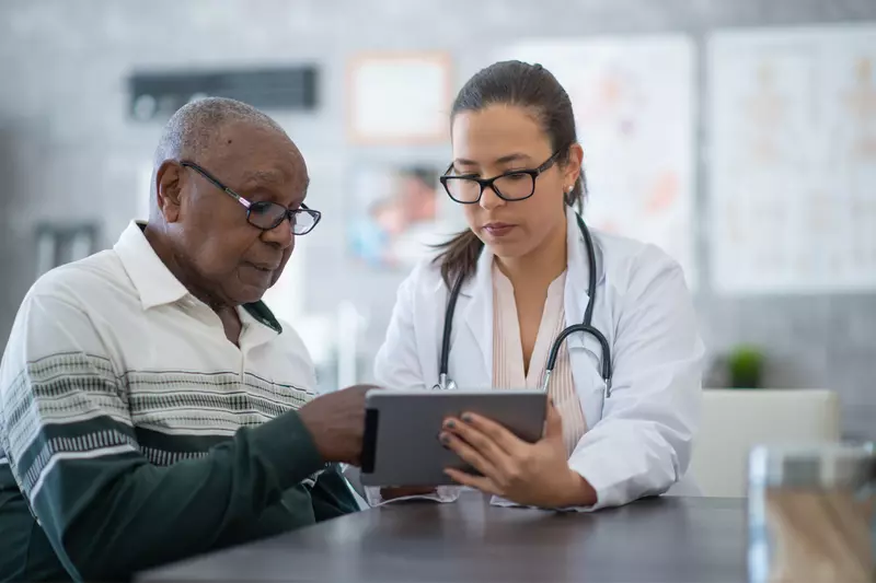 A Provider Goes Over a Patient's Chart with Him on a Tablet.