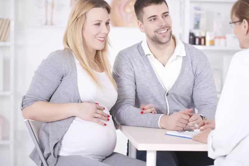 A pregnant couple consults a doctor.