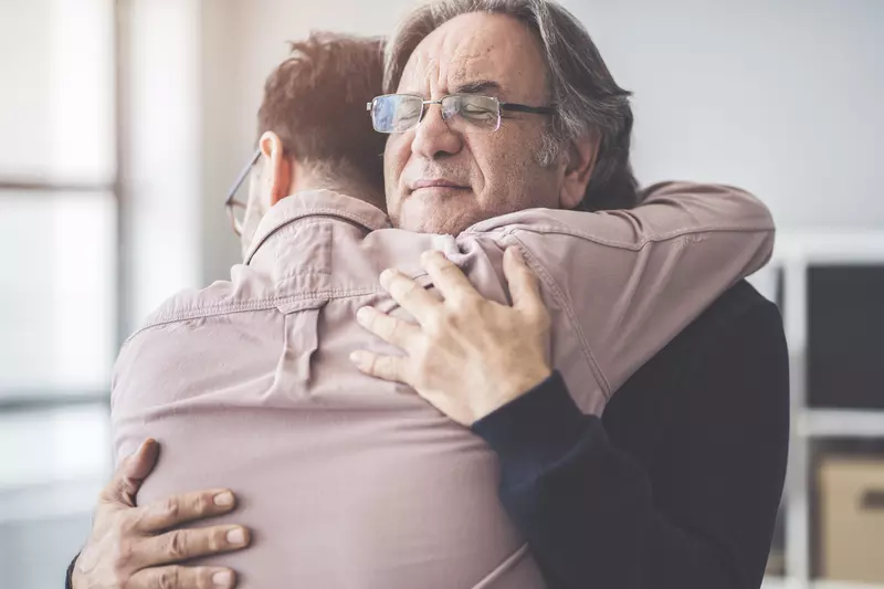 Two men are hugging comfort each other in their time of need.