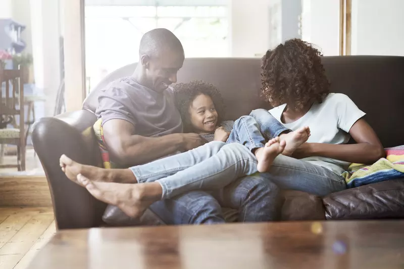 An African American family hangs out on the couch at home.