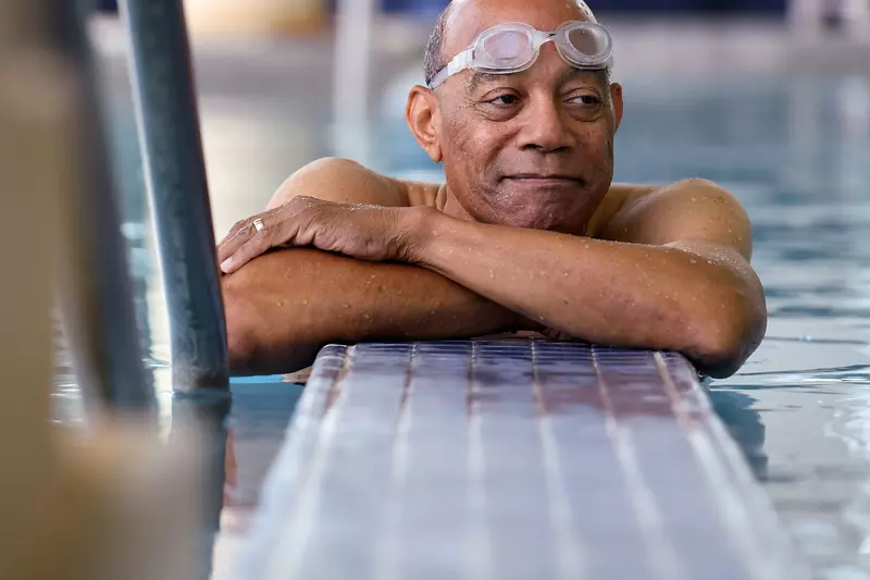 Elderly black man with goggles in a swiming pool.