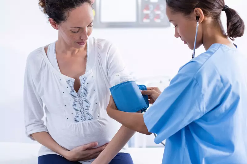 Pregnant woman gets her blood pressure checked at the doctor.