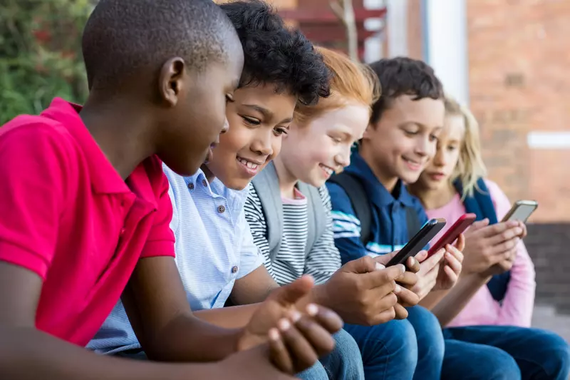 A group of kids use cell phones after school.