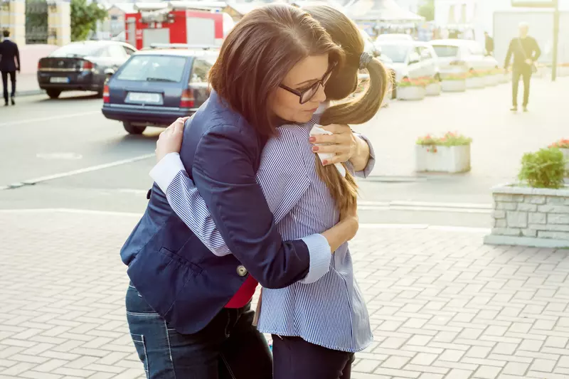 Two women comfort each other with a hug.