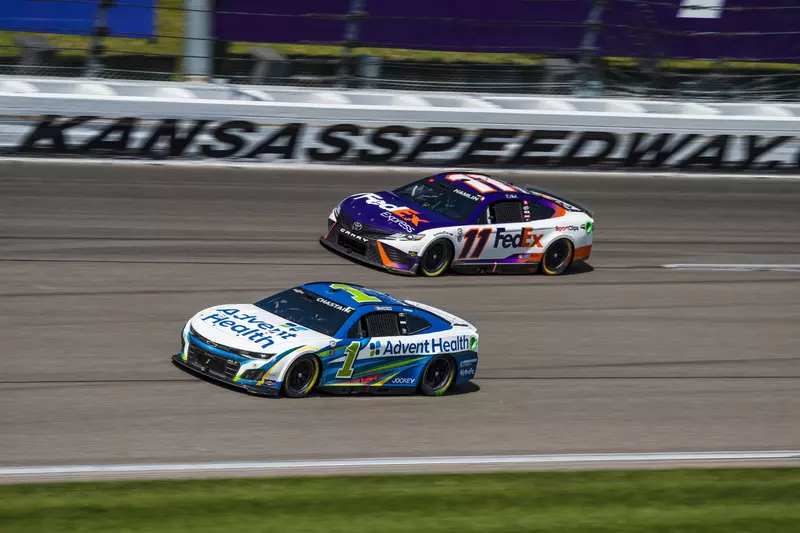 AdventHealth and FedEx NASCAR cars next each other while racing at Kansas Speedway.