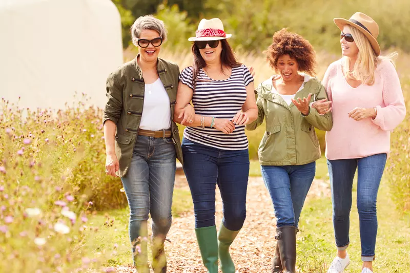 A Group of Inspiring Women Walk Through a Garden Smiling and Laughing