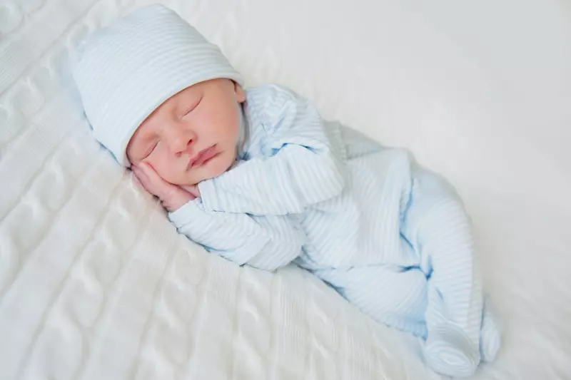 Newborn in blue clothes and a blue hat on a white blanket