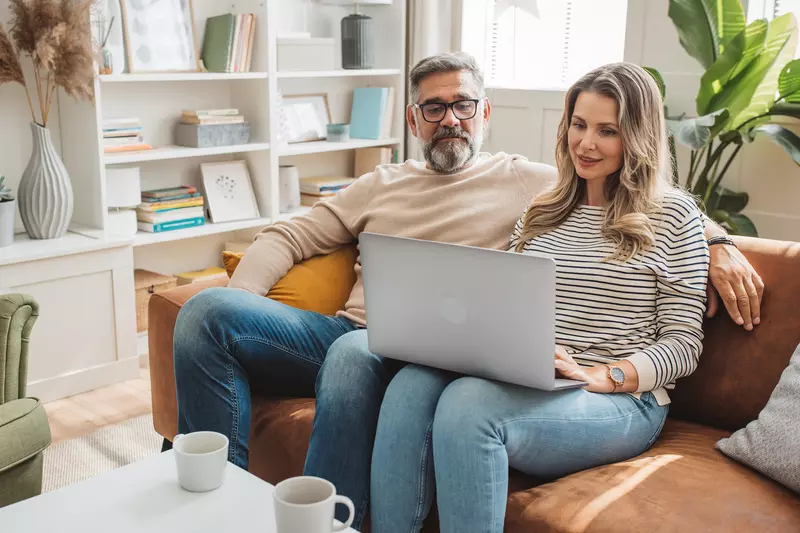 Couple looking at laptop togeter on couch. 