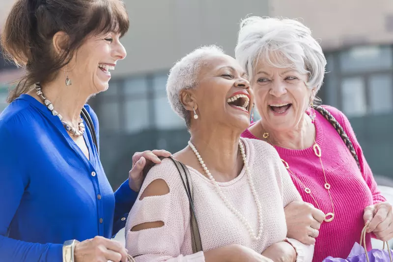 Three women laughing and shopping.