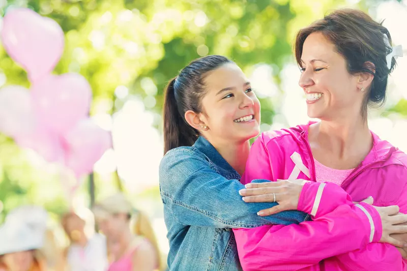 A daughter hugs her mother as they participate in a breast cancer walk.