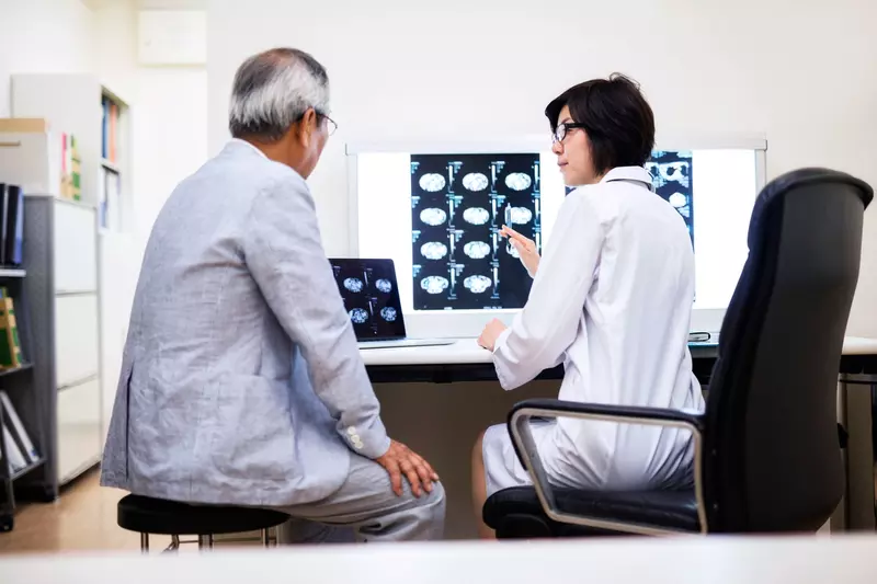 A doctor reviews brain scans with the older male patient