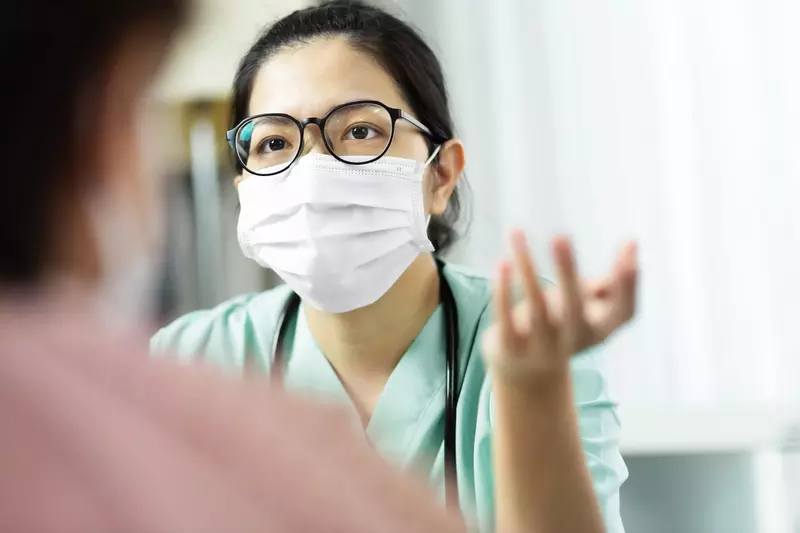 A doctor wearing a mask speaks with a patient. 