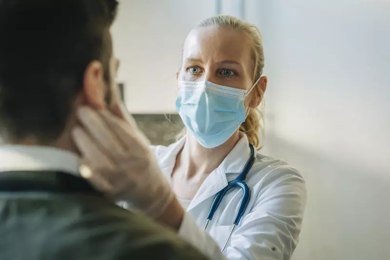 A doctor examines a patient while wearing a mask. 