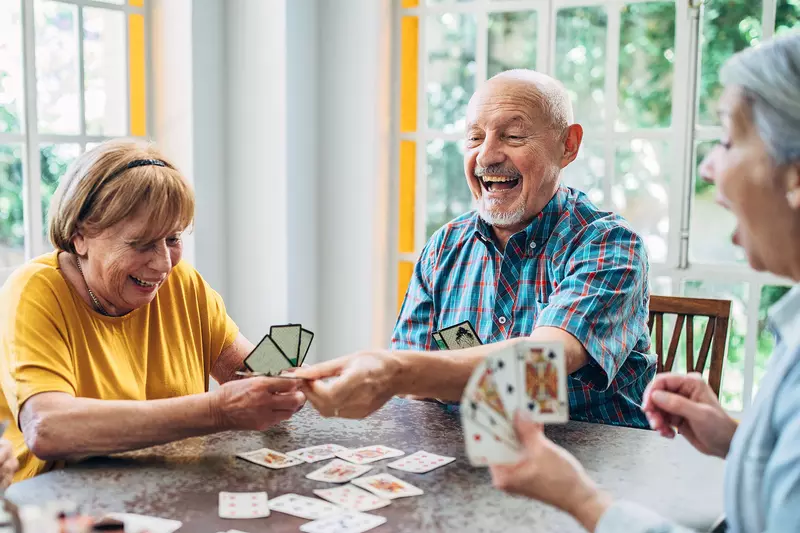 A group of senior adults play cards at home
