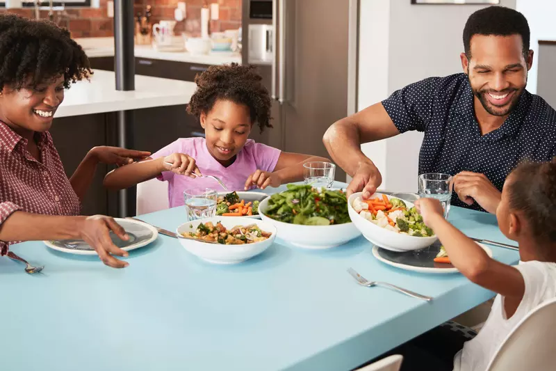 A young family sits down at the table to eat lunch