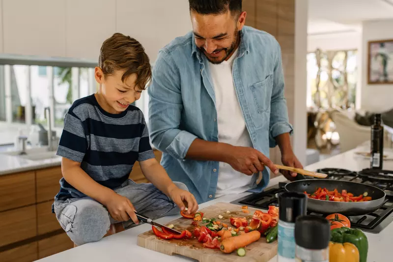 A father and son cook a healthy plant-based meal.
