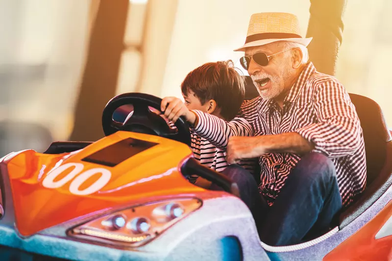 Grandfather and grandson playing in a bumper car