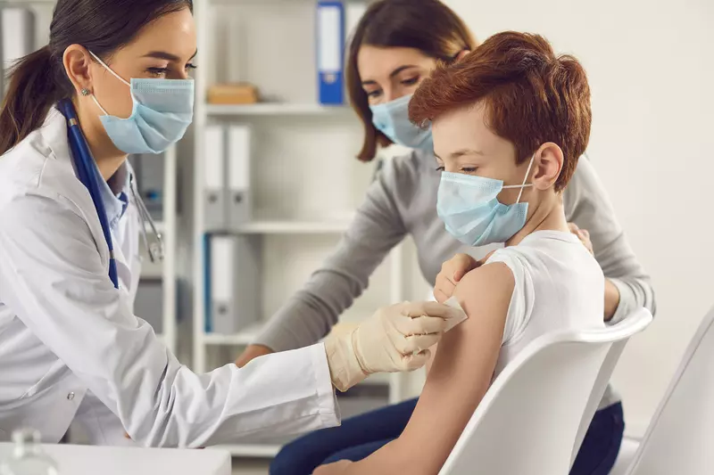 A teenager getting a vaccine shot by a doctor