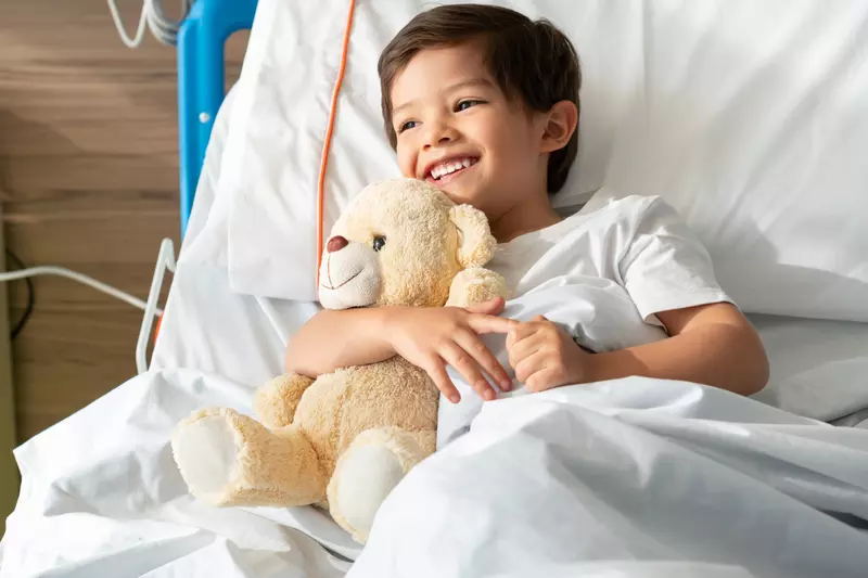 A little boy hugs his teddy bear while in the hospital.