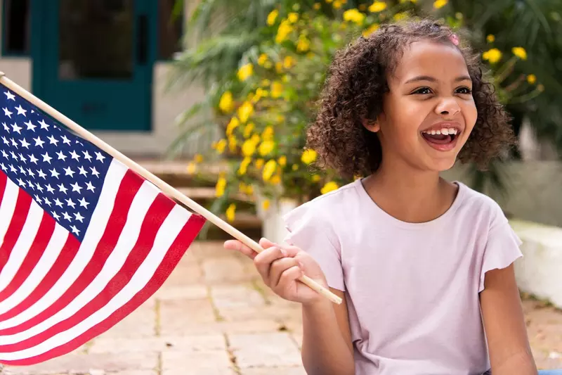 A young girl waves an American flag.