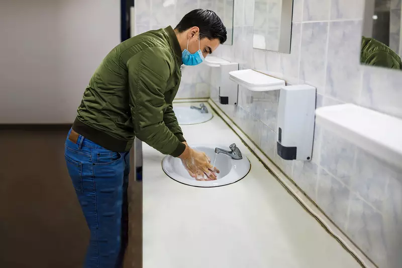 A man washing his hands in a public restroom.