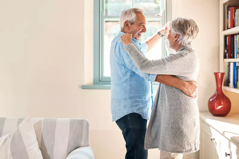 A mature couple dancing at home.