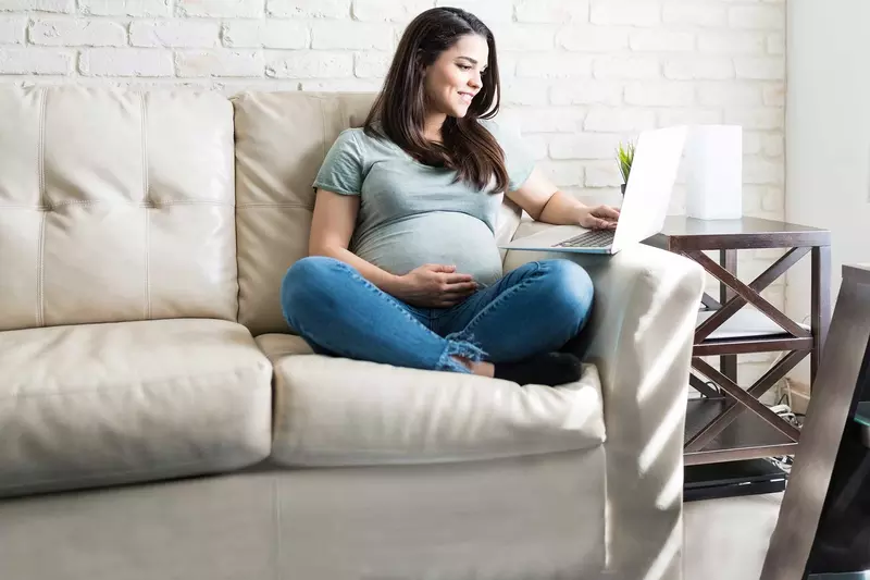 An expectant mother has a video call on her computer. 