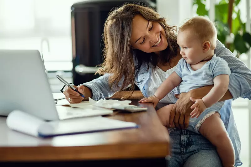 A mother and infant son at home in front of the computer. 