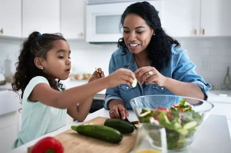 A mother and daughter making a salad together.
