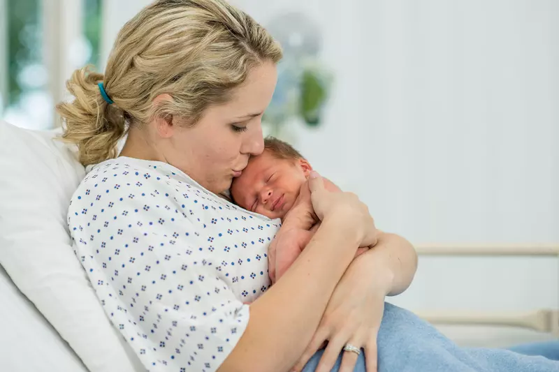A mother holds her new baby in the hospital.