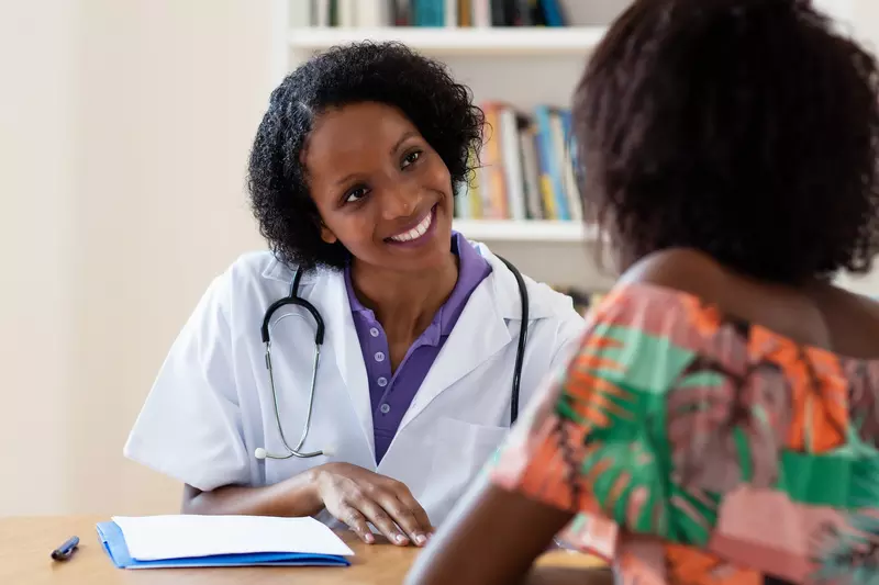 A smiling doctor talking with a female patient. 