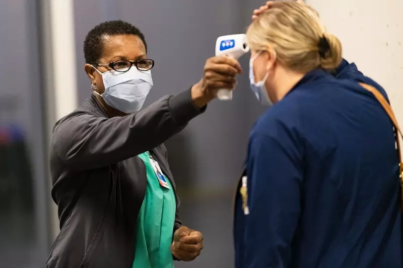 A health care worker temperature testing a patient. 