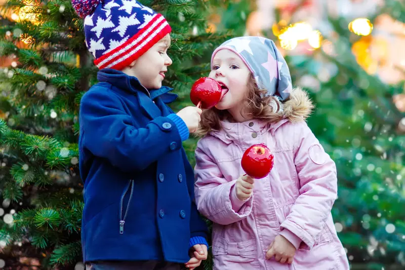 Two children at candy apples near the holidays.