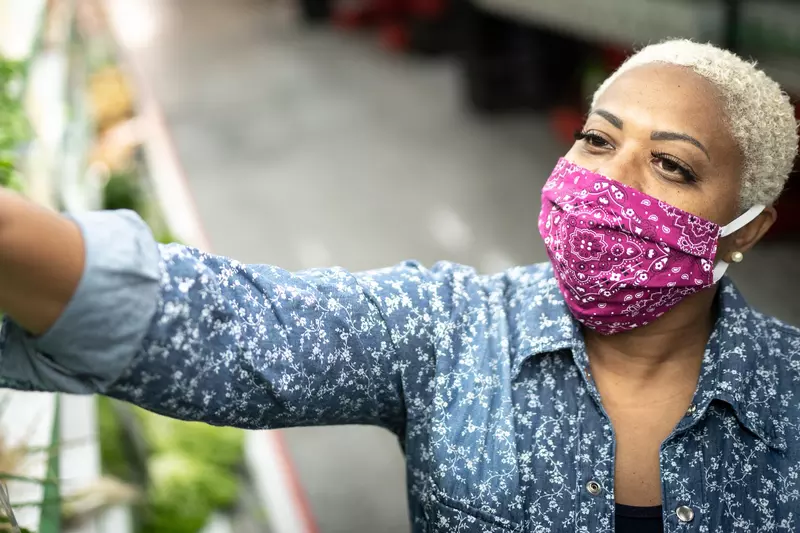 A woman wearing a cloth face mask at the grocery store.