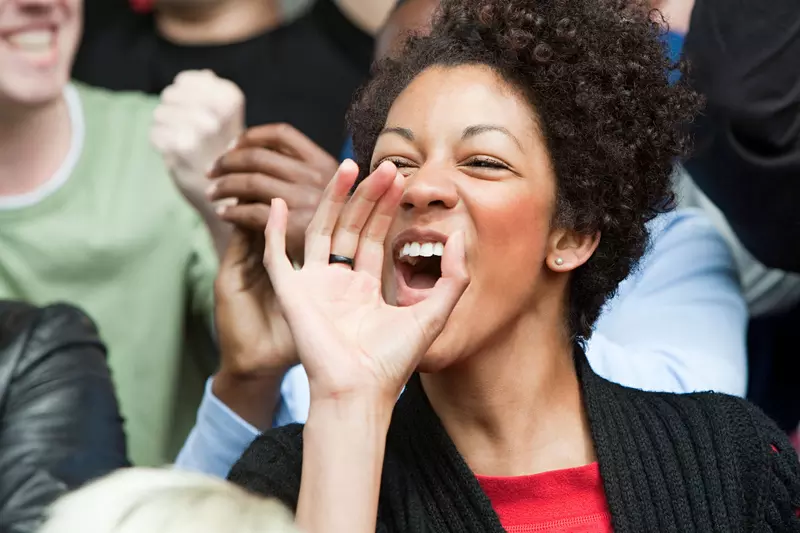 A woman cheers for her team at a sports game.