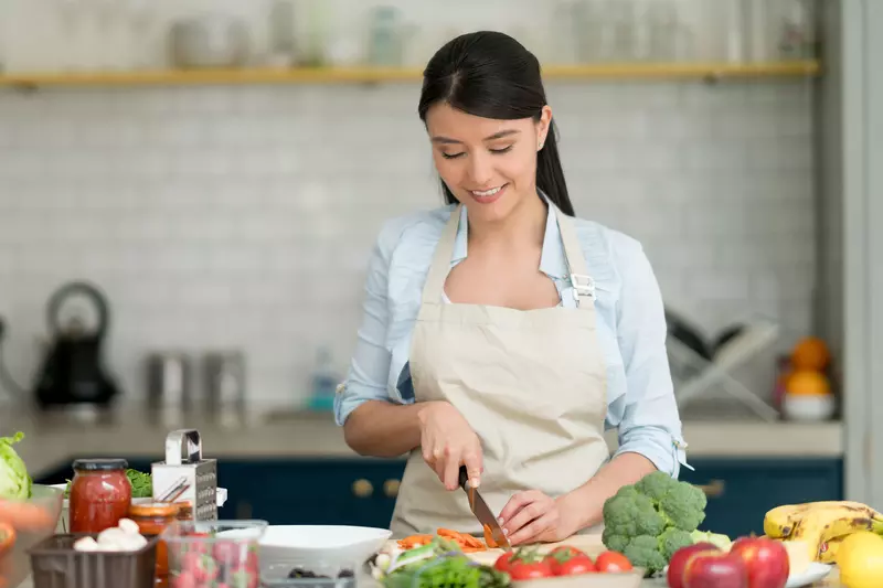 A Young Woman Chops Veggies in the Kitchen